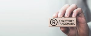 A person's hand holds a stamp that says Registered Trademark